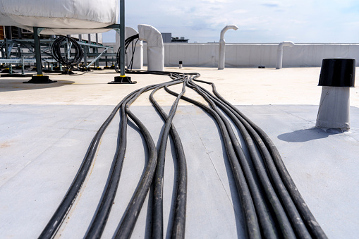 Laying cables and wires on the roof of an industrial building. Power supply for ventilation, air conditioning and air purification systems