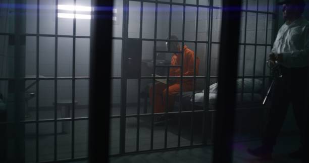 Prisoner sits on the bed, reads Bible in prison cell