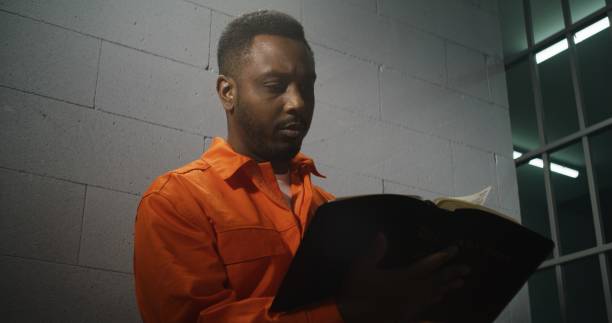 istock African American prisoner in orange uniform reads Bible 1608556300