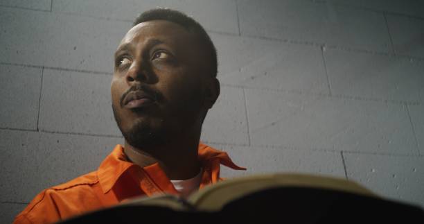 istock African American prisoner in orange uniform reads Bible 1608556945