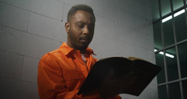 istock African American prisoner in orange uniform reads Bible 1608557938