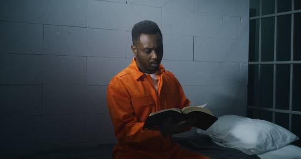 istock African American prisoner in orange uniform reads Bible 1608559971