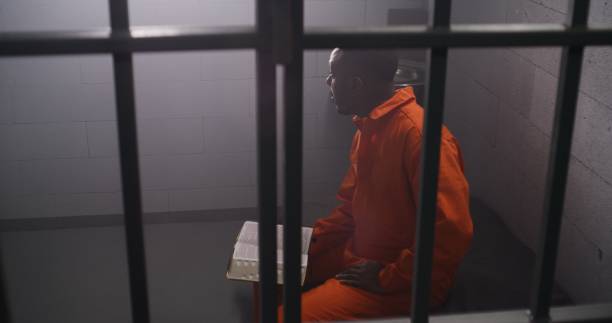 istock African American prisoner sits in prison cell, reads Bible 1608560975