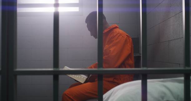 istock African American prisoner sits in prison cell, reads Bible 1608563500