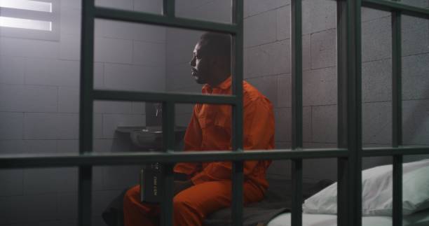 istock African American prisoner sits on bed, reads Bible in prison cell 1608564559