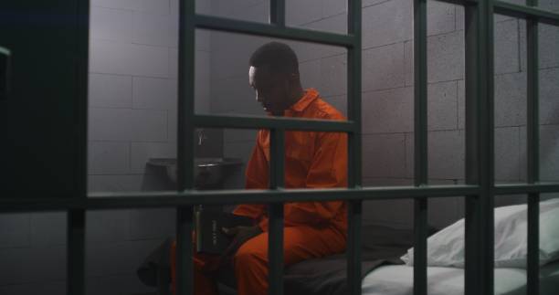 istock African American prisoner sits on bed, reads Bible in prison cell 1608566638