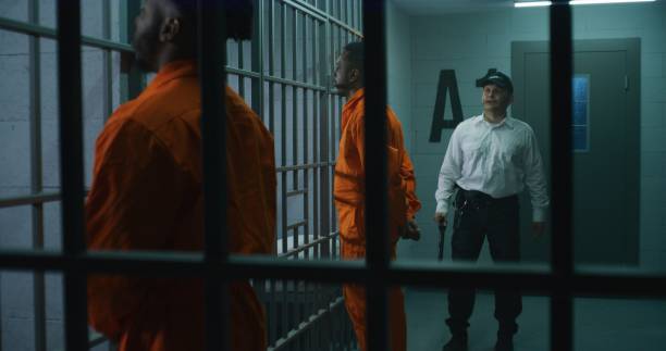istock Criminals stand face to cell with hands behind 1608596201