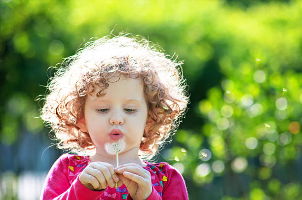istock Beautiful little curly girl blowing dandelion 160860434