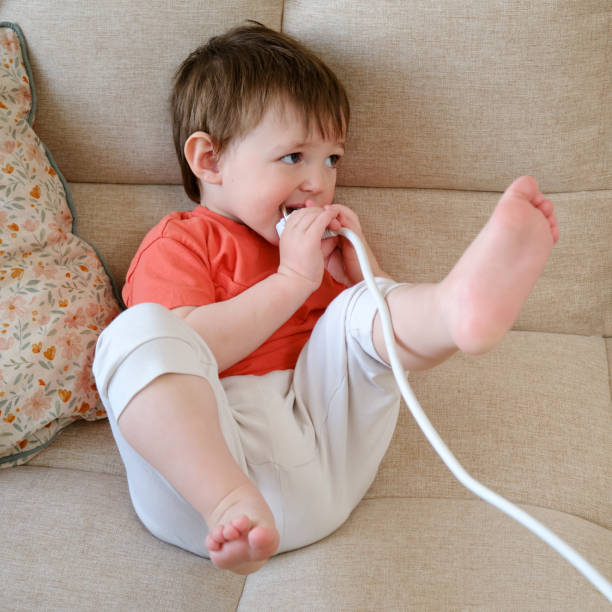 istock Baby is playing dangerously with an electrical cord inside the house, risking electric shock or injury. Kid aged about two years (one year ten months) 1608613480
