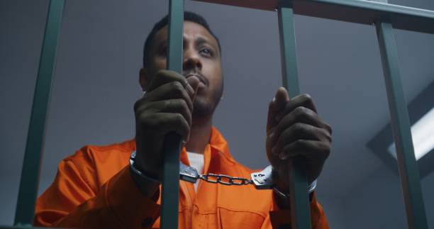 istock Inmate keeps hands in handcuffs on jail cell bars 1608613612