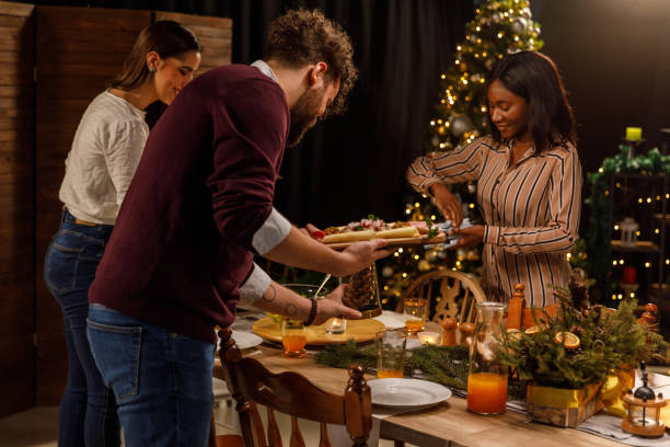 Group of friends working as a team and setting up the table for a Christmas dinner party stock photo