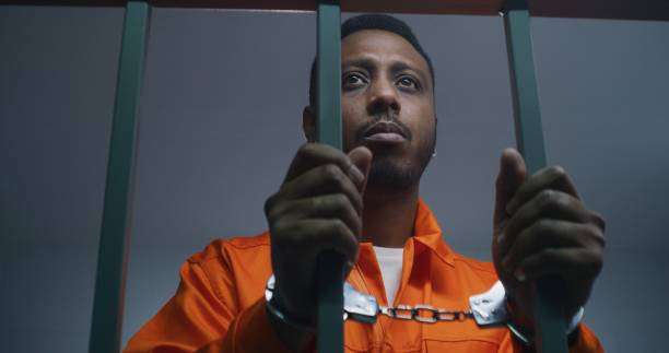 istock Inmate keeps hands in handcuffs on jail cell bars 1608615236
