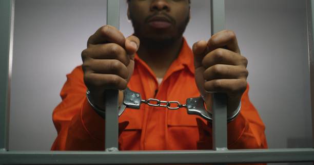 istock Prisoner keeps hands in handcuffs on jail cell 1608629511