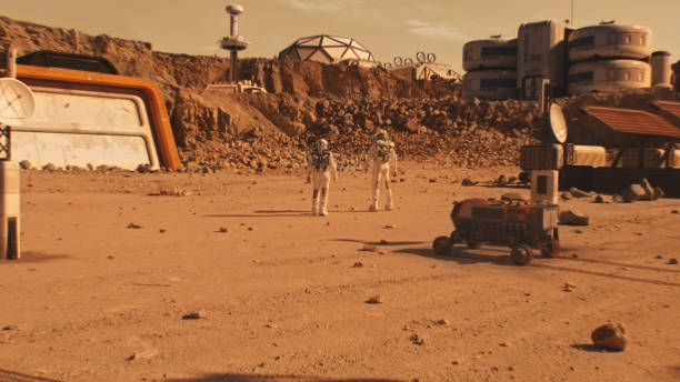 istock Two astronauts walk on Mars surface near scientific base 1608686315