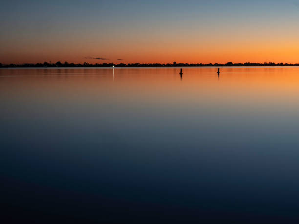 istock Posts in silhouette in lake at sunset 1608695508