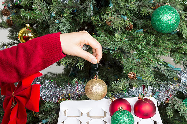 Putting away Holiday Objects Female hand putting away Golden holiday ornament into white card board box to end the season christmas decoration storage stock pictures, royalty-free photos & images