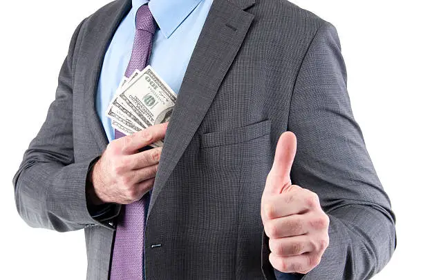 Photo of Dollars in a pocket of corrupted businessman showing thumb up