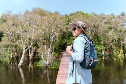 Asian man taking a walk on a bridge river and mangrove forest