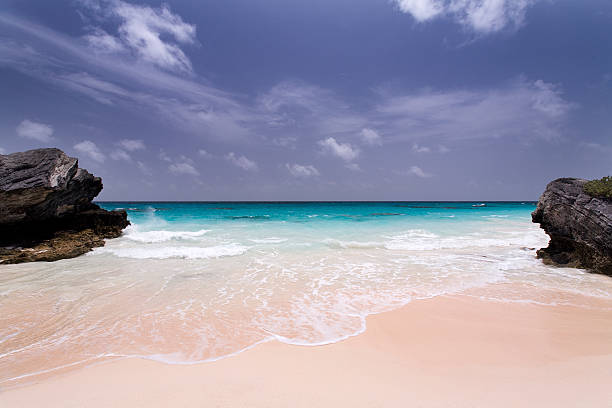 Deserted Pink Sand Beach in Bermuda Deserted beach framed by limestone rocks in Bermuda.  bermuda stock pictures, royalty-free photos & images