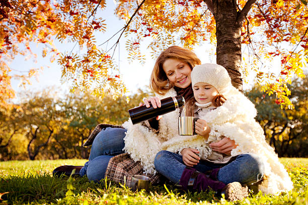 Mother and Daughter Drinking Hot Tea in Autumn Park stock photo