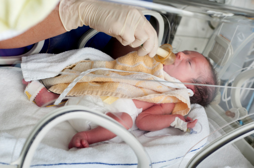 Newborn baby in incubator feeding