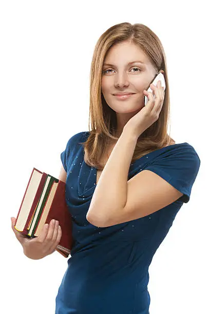 Beautiful young woman-student with books talking on cell phone, isolated on white background.