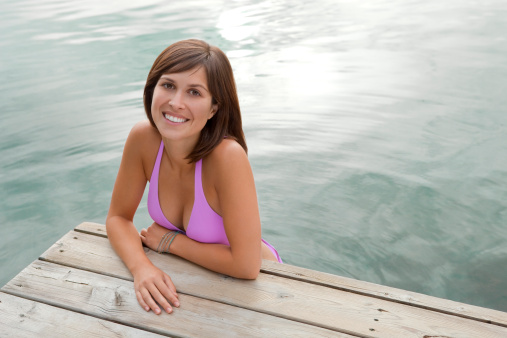 Beautiful woman in a pink bikini by the dock in a lake