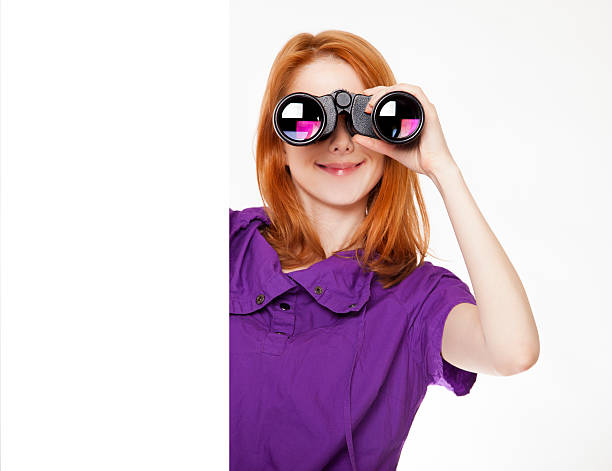 Teen red-haired girl with binoculars isolated on white backgroun stock photo