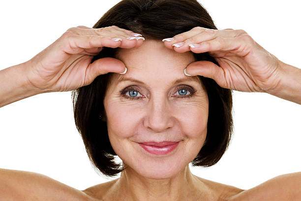 Woman stretching wrinkles Closeup of a mature woman stretching wrinkles on her forehead  wrinkled forehead stock pictures, royalty-free photos & images