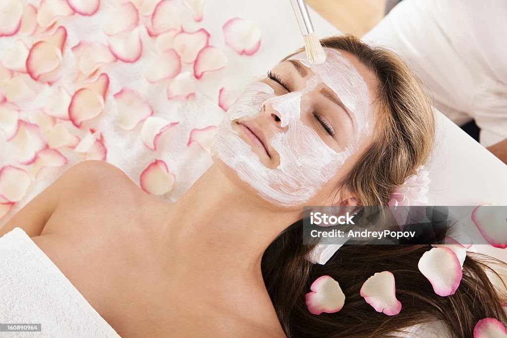 Beautician applying a face mask Beautician applying a face mask to a beautiful blonde woman lying relaxing in the salon with her eyes closed Beauty Product Stock Photo