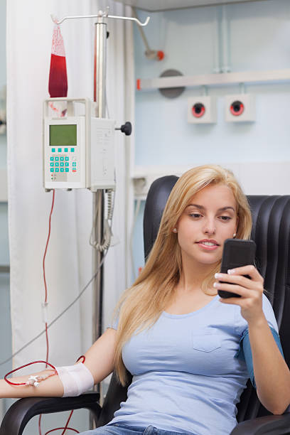 istock Female blood donor looking at her mobile phone 160893168