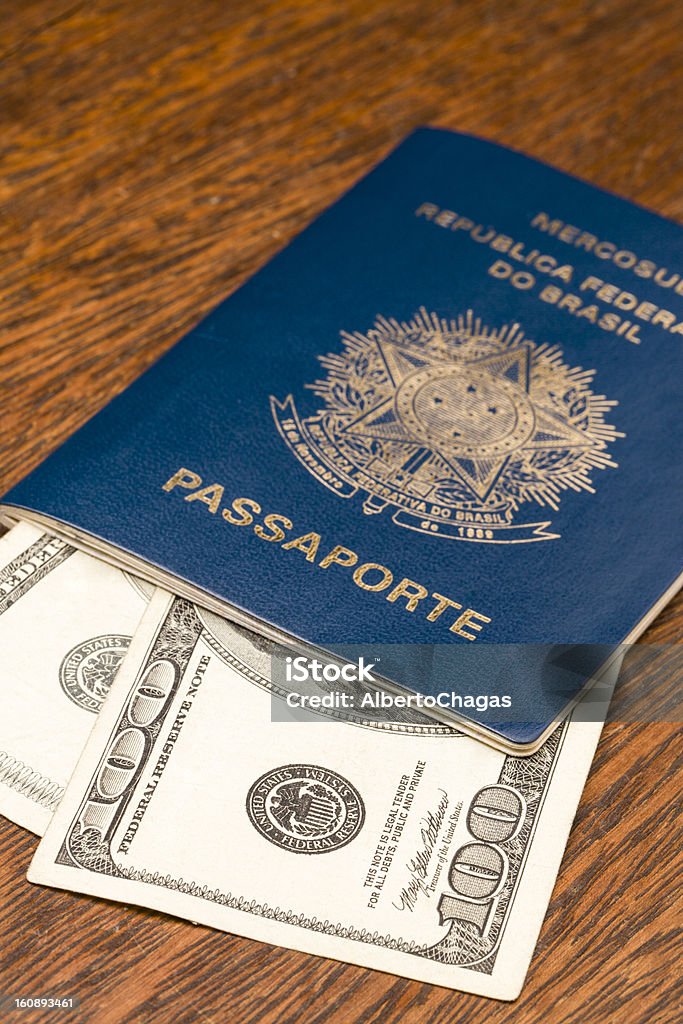 Brazilian Passaport with Dollar Brazilian Passport with Dollar bills over a wooden table. Brazil Stock Photo