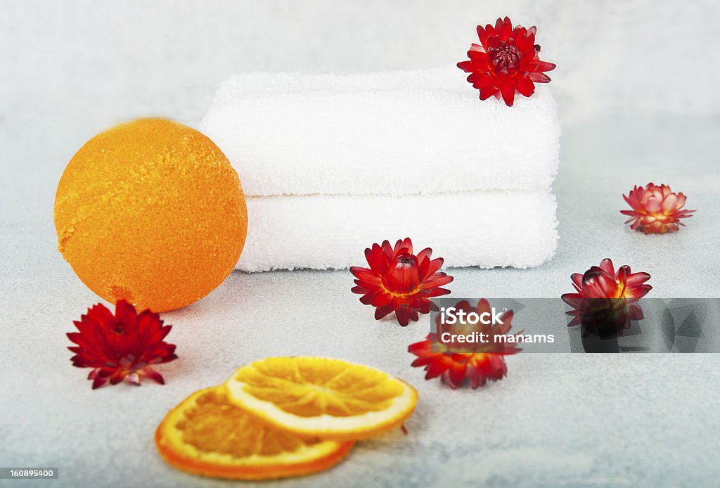 Spa in orange colors Two white terry towels, decorated with orange flowers, orange ball next to the bath, in the foreground dried orange segments Aromatherapy Stock Photo