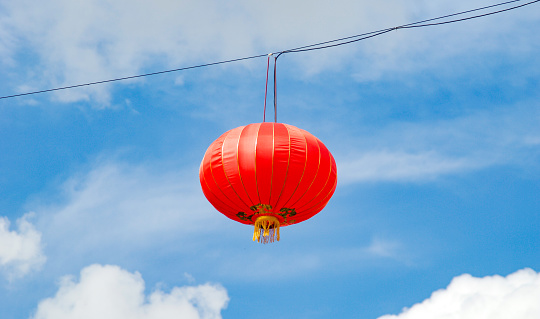 Single red Chinese lantern hanging in summer sky in Chinatown