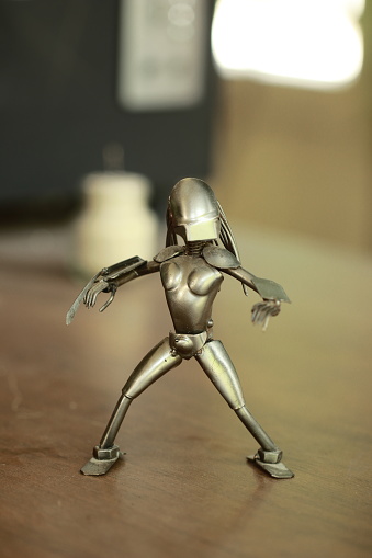 Metal figure of a robot on a wooden door, close-up