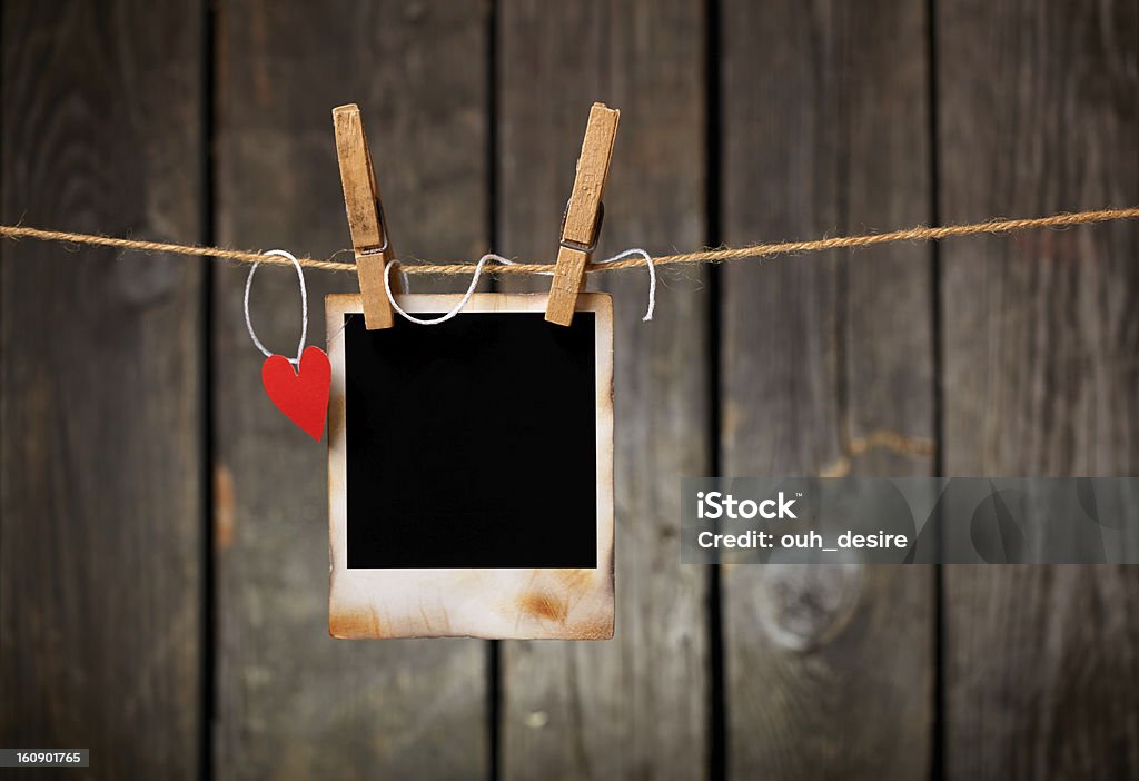 Blank vintage photo and red paper heart hanging on clothesline. Blank instant photo and small red paper heart hanging on the clothesline. On old wood background. Clothespin Stock Photo
