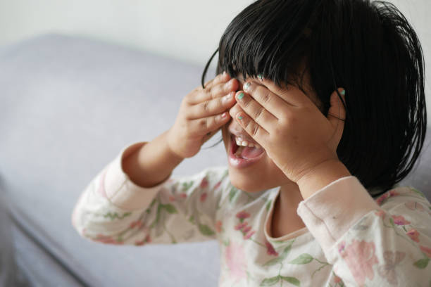 Cute Girl Rubbing Eyes While Standing Against Wall