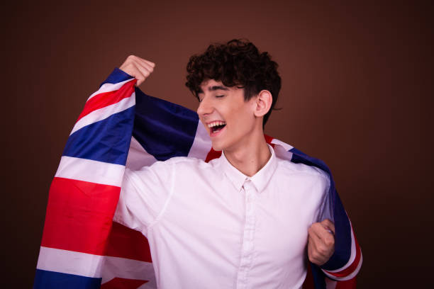 istock Young funny guy with british flag posing on brown background. 1609038451