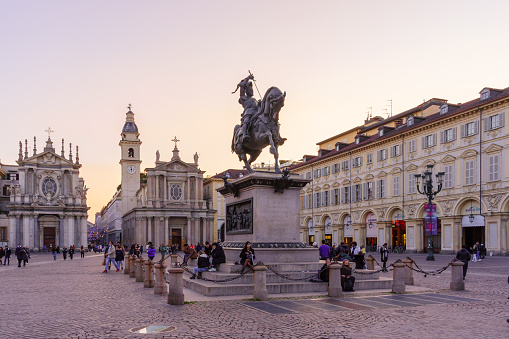 Turin, Italy - February 25, 2022: Sunset view of the Piazza San Carlo square, with locals and visitors, in Turin, Piedmont, Northern Italy