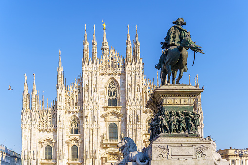 Milan, Italy - March 03, 2022: View of the Statue for Vittorio Emanuele II (dated 1879), and the Cathedral (Duomo) in the background, in Milan, Lombardy, Northern Italy