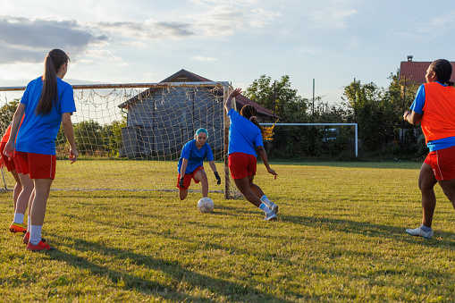 Group of young women playing soccer at an outdoor field.