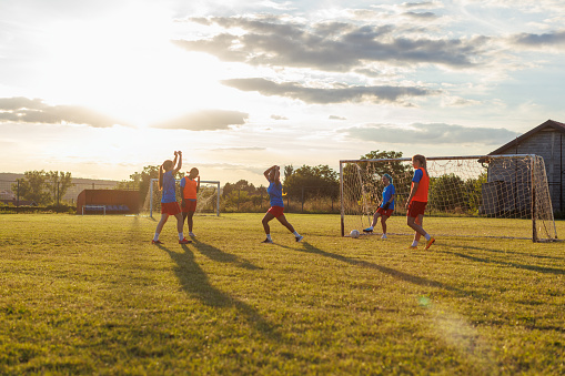 Group of young women playing soccer at an outdoor field.