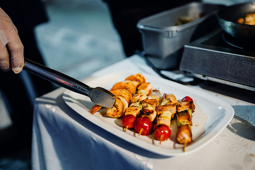 Close up of professional chef serving salmon skewers at outdoor party
