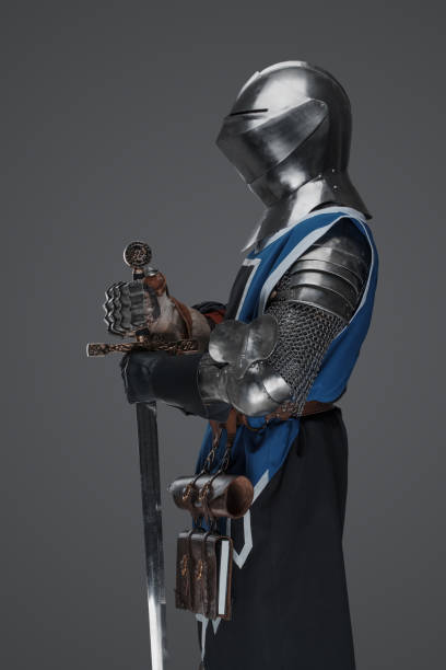 istock Medieval guard dressed in armor and blue surcoat holding a sword 1609151168