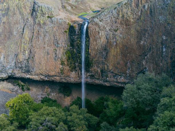 istock Powerful waterfall cascades down the side of a towering mountain. 1609181091