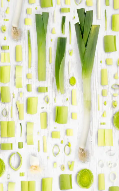 Abstract background made of Leek vegetable pieces, slices and leaves on wooden background.