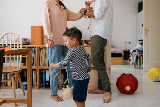 istock Cute White Boy Playing by Himself, with his Unrecognizable Parents in the Background 1609207268