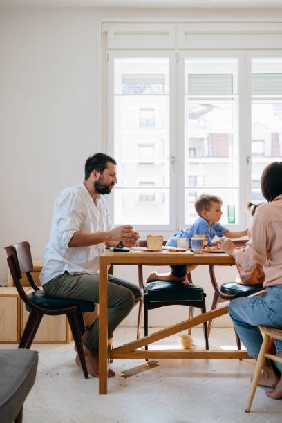 istock Happy Father and Unrecognizable Mother Sitting at the Dining Table with their Son, Having Breakfast 1609207844