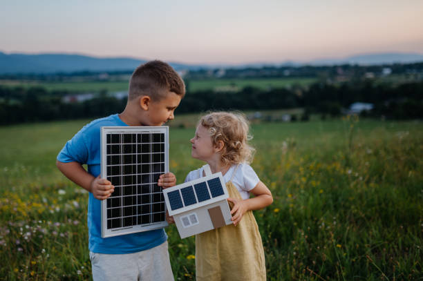 istock Young boy holding solar panel and his sister holding model of house with installed solar panels. 1609228069