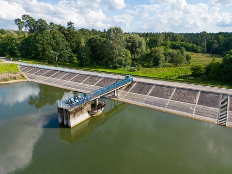 Aerial drone view of a concrete hydroelectric dam with a pump station situated on a serene lake
